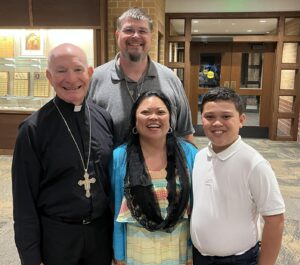 Thom Sisson and his family stand with Archbishop Emeritus George Lucas, smiling after Mass, reflecting their shared faith and active participation in parish life.